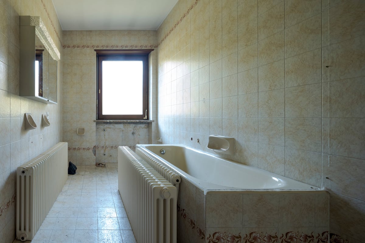 Interior of empty old villa bathroom to renovate worn tiles outdated fixtures needs remodel