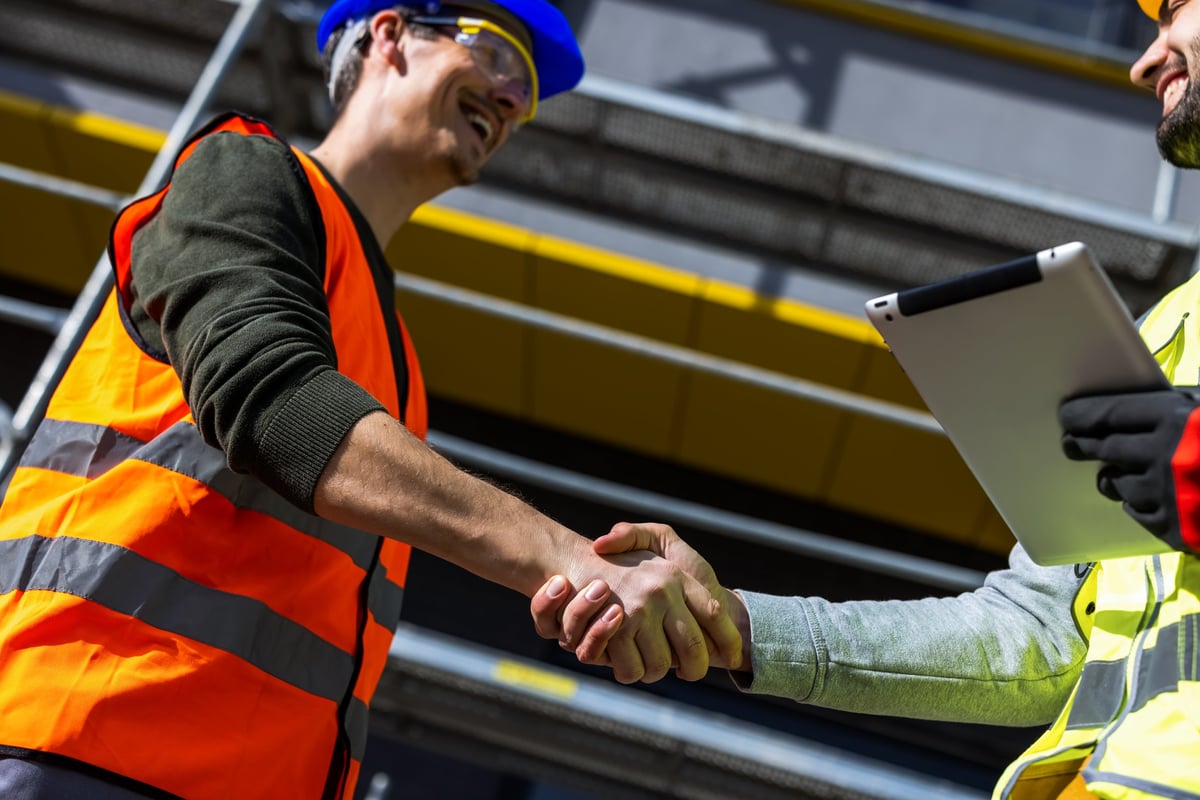 Professional engineers in safety gear shaking hands symbolizing successful partnership