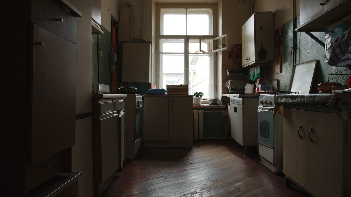 Old kitchen of a communal flat with dated cabinets and worn surfaces ready for renovation